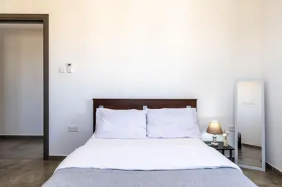 a bedroom with a large bed with white sheets at Maryam's 2-BR Apt Facing Larnaca Harbor With Pool in Larnaka
