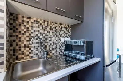 a kitchen counter with a sink and a microwave at Maryam's 2-BR Apt Facing Larnaca Harbor With Pool in Larnaka