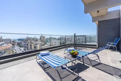 a balcony with a table and chairs on a roof at Maryam's 2-BR Apt Facing Larnaca Harbor With Pool in Larnaka