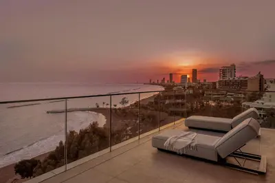a balcony with a view of the ocean at sunset at Amathus Residences in Limassol