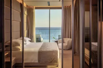 a bedroom with a bed and a view of the ocean at Amathus Residences in Limassol