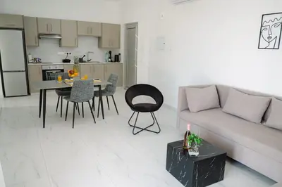a living room with a couch and a table and a kitchen at Nissi Route 76 in Ayia Napa
