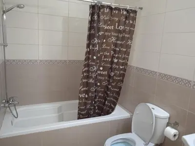 a bathroom with a shower curtain with a toilet and a tub at Xylophagou Larnaca Ayia Napa Sunshine Apartments in Xylophaghou