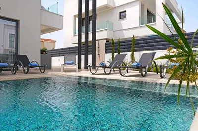 a swimming pool with chairs next to a building at Levanda Platinum - Sunrise Sea View in Protaras