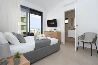 a bedroom with a bed and a tv and a chair at Levanda Platinum - Sunrise Sea View in Protaras