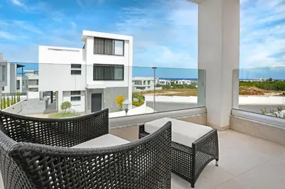 a balcony with two wicker chairs and a large window at Levanda Platinum - Sunrise Sea View in Protaras