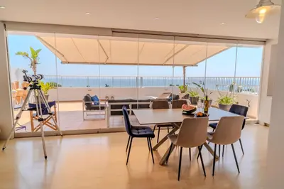 a dining room with a table and chairs and a camera at Blue Penthouse Mackenzie in Larnaka