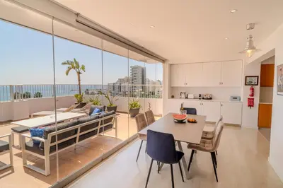 a kitchen and living room with a table and chairs at Blue Penthouse Mackenzie in Larnaka