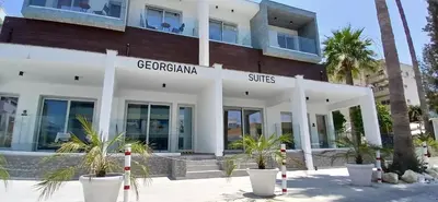 a building with palm trees in front of it at Georgiana Suites in Larnaka