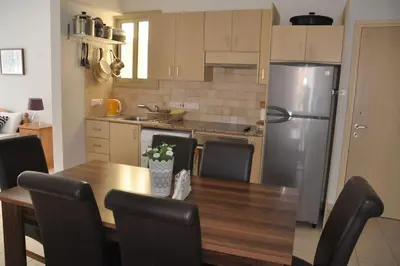 a kitchen with a wooden table and a stainless steel refrigerator at Eliza Suite at Pernera Beach in Protaras