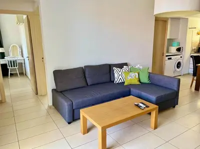 a living room with a blue couch and a coffee table at Eliza Suite at Pernera Beach in Protaras
