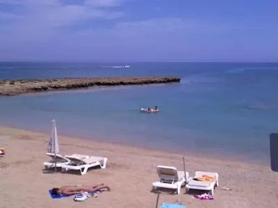 a beach with chairs and a group of people on it at Aphrodite Sea View Suite in Protaras