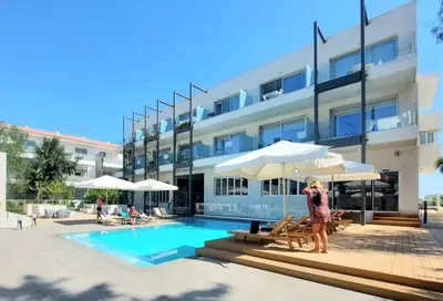 a man standing next to a swimming pool next to a building at Mythical Sands - Evexia in Paralimni