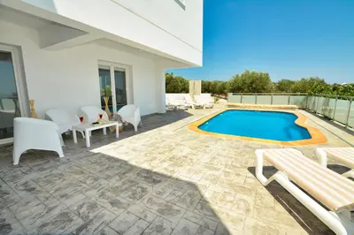a patio with a pool and chairs and a house at Villa Christina in Ayia Napa