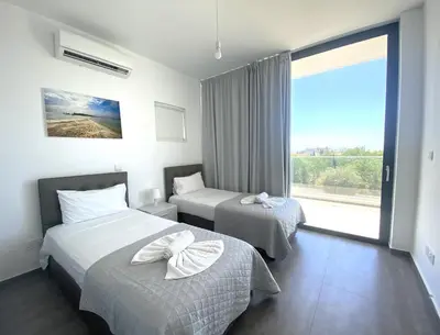 a hotel room with two beds and a large window at NISSI PEARL Holiday Villas Ayia Napa in Ayia Napa