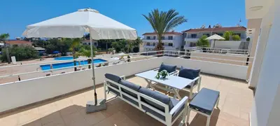 a patio with a table and chairs and an umbrella at Nissi 3 Pool View 2 Bedroom Apartment with Large Veranda in Ayia Napa