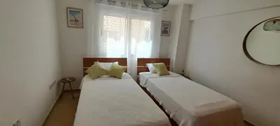 two beds in a small room with a window at Nissi 3 Pool View 2 Bedroom Apartment with Large Veranda in Ayia Napa