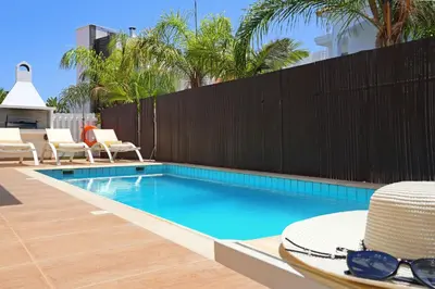 a swimming pool with a hat and sunglasses next to a fence at Villa Artemis - 30m from Pernera Beach in Protaras