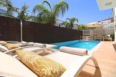a swimming pool with two chaise lounge chairs next to a fence at Villa Artemis - 30m from Pernera Beach in Protaras