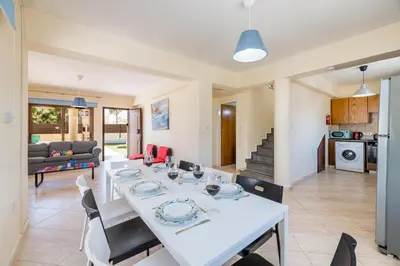 a dining room and living room with a table and chairs at Villa Sarah in Ayia Napa