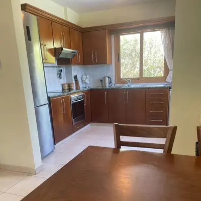 a kitchen with wooden cabinets and a table and a window at Villa Annalisarose in Ayia Napa