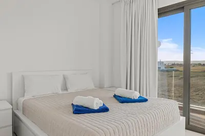 a white bedroom with a bed with blue towels on it at Serenity Waves Villa 12 in Sophtadhes