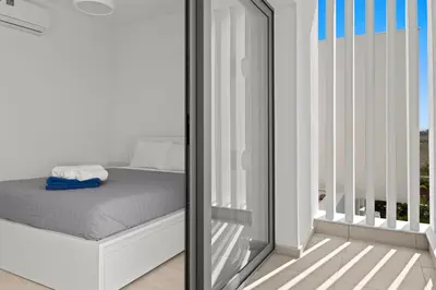 a white bedroom with a bed and a window at Serenity Waves Villa 10 in Sophtadhes