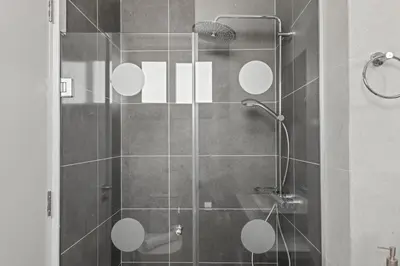 a bathroom with a shower with white circles on the wall at Serenity Waves Villa 16 in Larnaka