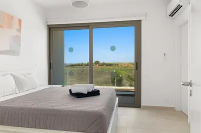 a bedroom with a bed and a large window at Serenity Waves Villa 17 in Larnaka