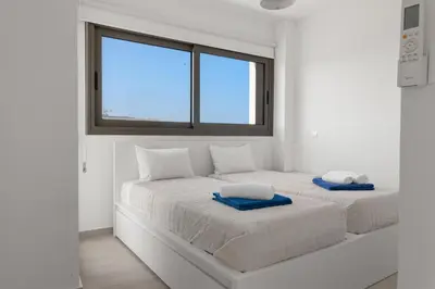 two beds in a white room with a window at Serenity Waves Villa 26 in Larnaka