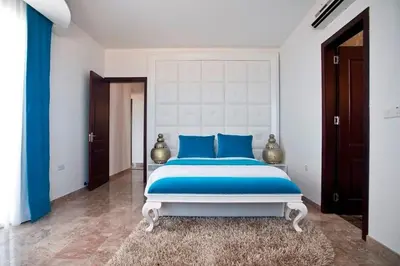 a bedroom with a large bed with blue pillows at Exquisite Protaras Villa Villa Bulat 4 Bedrooms Beachfront in Protaras
