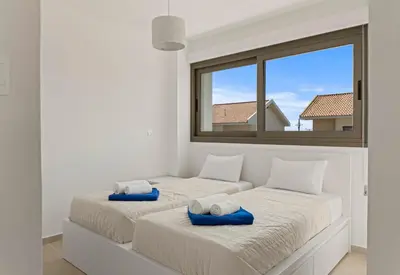 two beds in a white room with a window at Serenity Waves Villa 22 in Larnaka