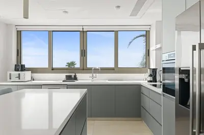 a kitchen with white cabinets and a large window at Serenity Waves Villa 4 in Sophtadhes