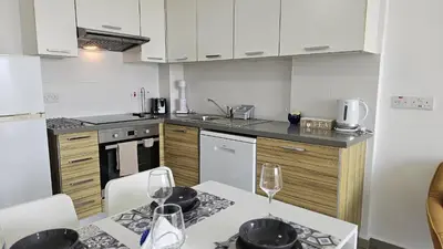 a kitchen with white cabinets and a table with wine glasses at STAY Arpa Suite in Protaras