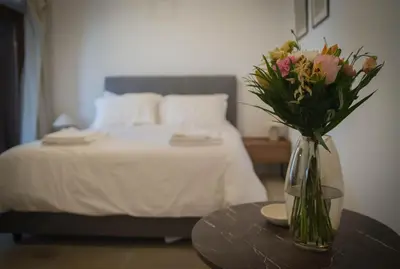 a vase of flowers on a table next to a bed at AROMA DRYOS in Kato Drys