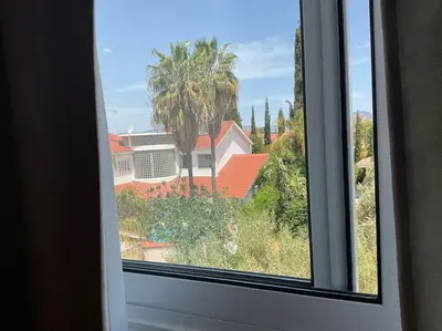 a window with a view of a house and palm trees at Central cozy apt in quiet area in Engomi in Nicosia