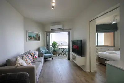 a living room with a couch and a bed and a television at Palmove Luxurious Beachfront Apt in Larnaka