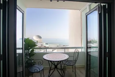 a balcony with a table and chairs and a view of the ocean at Palmove Luxurious Beachfront Apt in Larnaka