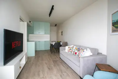 a living room with a gray couch and a kitchen at Palmove Luxurious Beachfront Apt in Larnaka