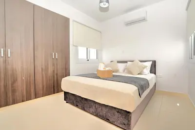 a bedroom with a large bed and wooden cabinets at La Bella Nissi Villa in Ayia Napa