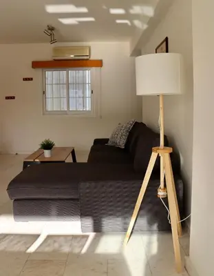 a living room with a black couch and a lamp at Sunny 2 bedroom flat in Engomi in Engomi
