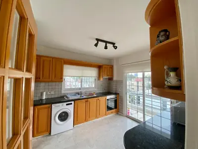 a kitchen with wooden cabinets and a washing machine at Sunny 2 bedroom flat in Engomi in Engomi