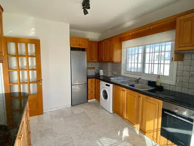 a kitchen with wooden cabinets and a washer and dryer at Sunny 2 bedroom flat in Engomi in Engomi