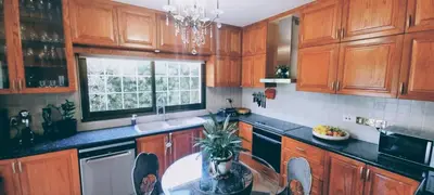 a kitchen with wooden cabinets and a sink and a window at Salty Sunset Holiday Home in Limassol