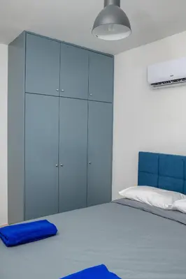 a bedroom with a large bed with blue cabinets at Olympia Flat 104 in Larnaka