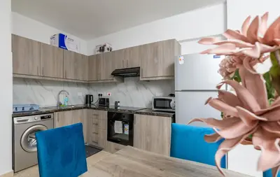 a kitchen with a refrigerator and a table with blue chairs at Olympia Flat 104 in Larnaka