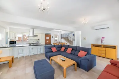 a living room with a blue couch and a kitchen at Villa Lindo in Protaras
