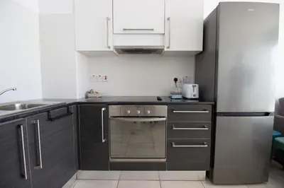 a kitchen with black cabinets and a stainless steel refrigerator at Prime Protaras Seafront Apt in Protaras