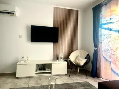 a living room with a white desk and a television on the wall at Nissi Golden Sands Apartment D01 in Ayia Napa