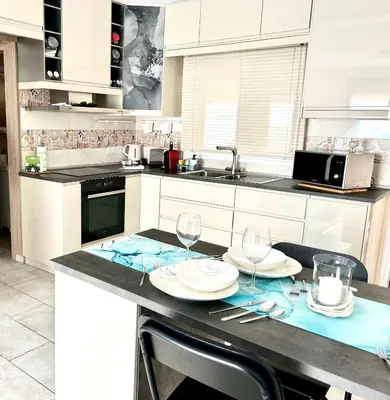 a kitchen with a table with plates and wine glasses at Nissi Golden Sands Apartment D01 in Ayia Napa